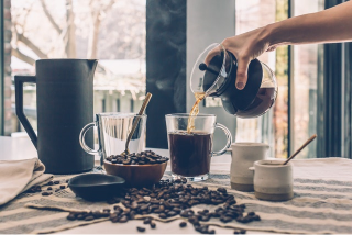 Filling clear glass mug with coffee